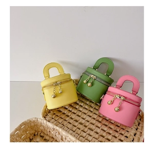 Détail de mini sacs seaux en rose, vert et jaune avec des tirettes dorées à boule