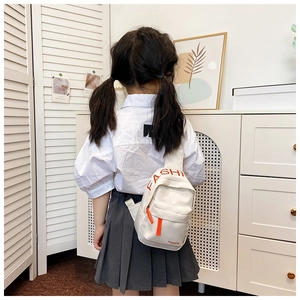 Detail of white leather kids chest bag with orange FASHION text and adjustable strap