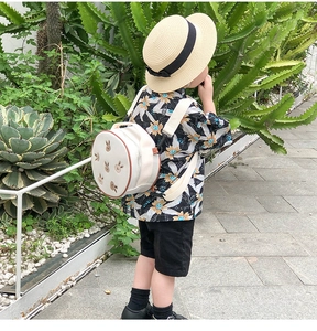 Détail d'un sac à dos rond crème pour enfant avec broderie lapin dans un jardin