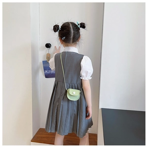 Detail view of a green semi-circle PU crossbody bag on a girl with pleated grey dress