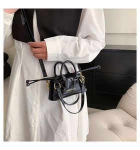 Detailed close-up of a glossy black patent leather mini shell bag with fashion lettering