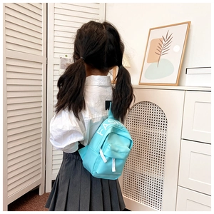 Close-up of sky blue kids crossbody bag with white FASHION lettering on adjustable strap