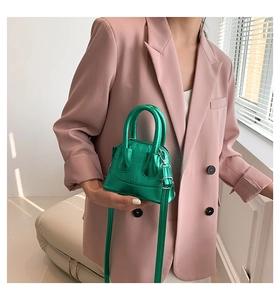 Detail of neon green mini shell bag with crocodile texture and metallic finish