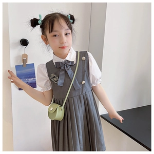 Detailed view of girl's academic dress with pleated grey skirt and mini crossbody bag