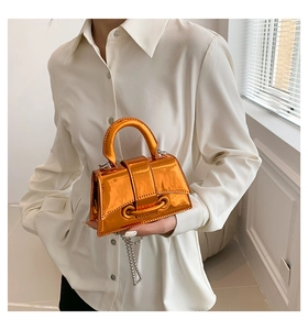 Detailed view of neon orange metallic mini handbag with silver chain strap and mirror finish