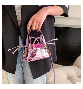 Detail of metallic pink patent leather shell bag featuring inner drawstring and logo