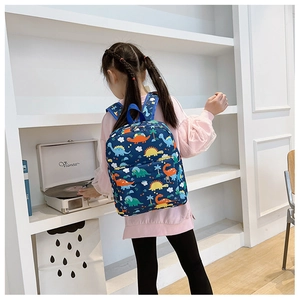 Detail view of children's blue dinosaur backpack showing zipper pockets and waterproof canvas