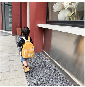 Enfant marchant avec un sac à dos en toile jaune et beige orné du chiffre 90