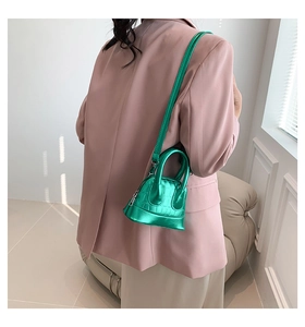 Miniature metallic green shell bag with crocodile pattern texture shown on model