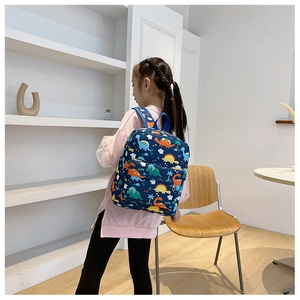 Side view of kid wearing a blue backpack with colorful cartoon dinosaur prints and cloud patterns