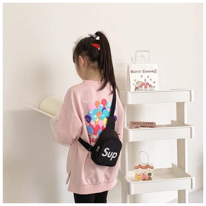 Close-up of kids black canvas chest bag with white letter print worn by a child