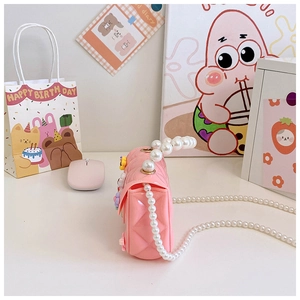 Détail du mini sac en silicone rose avec motif matelassé, fleur et chaîne en perles