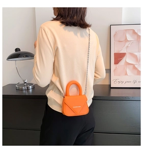 Orange Mini-Umhängetasche mit Silberkette und weißer Aufschrift an einem Model
