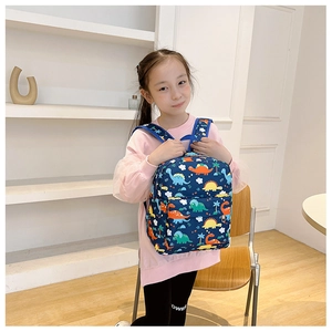 Detail of dark blue children backpack with colorful dinosaur prints worn by a girl