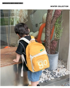 Détail d'un sac à dos enfant jaune et blanc avec lettrage basketball sur un enfant