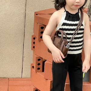 Dettaglio mini borsa in pelle marrone abbinata a un top in maglia a righe alla moda per bambine