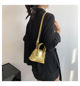 Detailed view of mini shell bag with golden crocodile pattern texture and top handles
