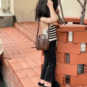 Bambina che indossa una mini borsa in pelle marrone con doppi manici e tracolla regolabile