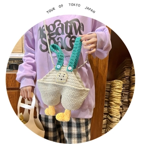 Close-up of handmade crochet bag with pearl strap, 3D character design, and knit texture