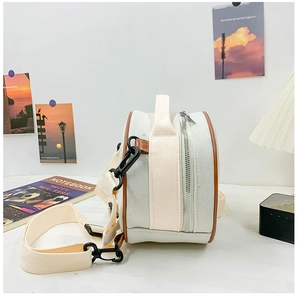 Détail du sac rond en toile avec bordure en cuir marron et fermeture éclair métallique