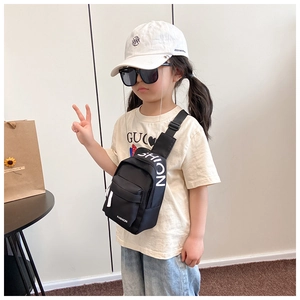 Close-up of kids black nylon crossbody bag with fashion letter print and street style props