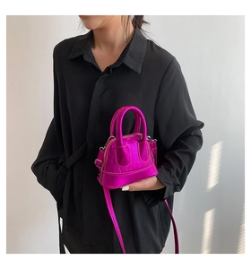 Mini shell crossbody bag in metallic purple crocodile pattern shown on model with shoulder strap