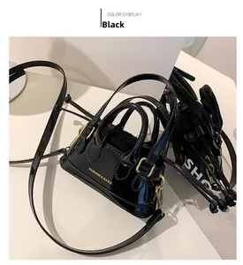 Close-up of black patent leather shell bag with gold hardware and logo detail