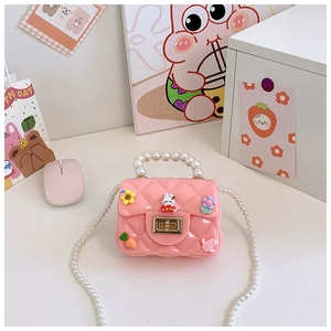Gros plan d'un mini sac en silicone rose avec poignée en perles et breloques cartoon