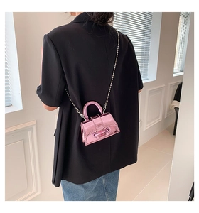 Pink metallic mini crossbody bag with chain strap shown on model from back view