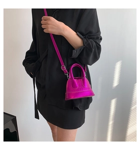 Detail of fuchsia shell bag with crocodile pattern and adjustable shoulder strap