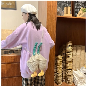 Detail of handmade crochet overall bag with pearl strap on a purple sweatshirt