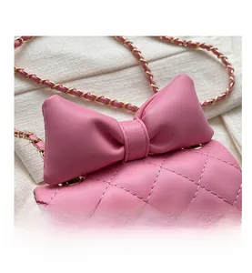 Detailed view of pink quilted mini crossbody bag with leather bow and gold chain strap