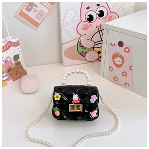 Détail d'un sac enfant en silicone noir matelassé avec breloques cartoon et perles