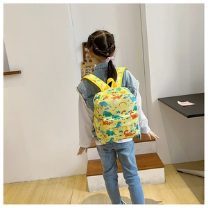Detailed view of yellow toddler backpack with colorful dinosaur patterns worn by a child