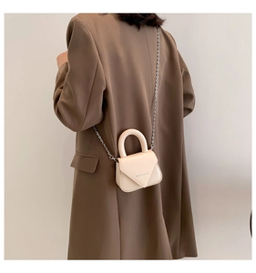 Detailansicht der cremefarbenen Mini-Umhängetasche mit Kette am Model getragen