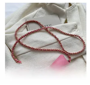 Detailed view of pink quilted crossbody bag with oversized bow and chain strap