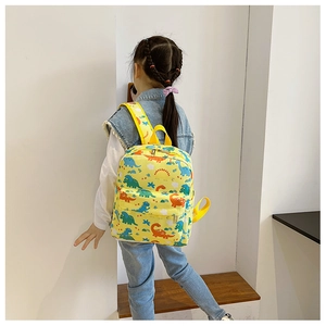 Detail of yellow children's backpack featuring colorful cartoon dinosaur prints on canvas