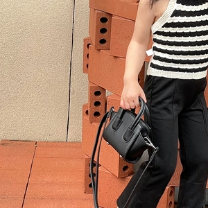 Scatto all'aperto di una mini borsa a conchiglia nera per bambina con manico e tracolla