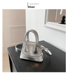 Detail view of silver mini shell bag with crocodile texture and cylindrical handles