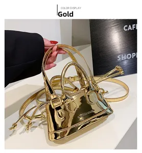 Close-up of metallic gold patent leather shell bag with twin handles and fashion logo