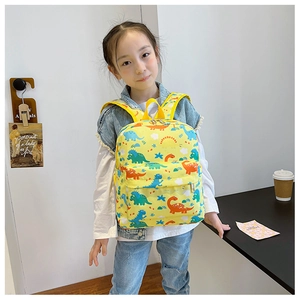 Kids yellow dinosaur backpack with adjustable straps worn by a young girl in a room