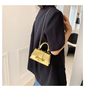 Detail of a mini gold mirror metallic handbag with beaded chain strap on a dark blazer