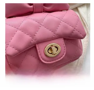 Detailed macro view of pink quilted handbag featuring gold twist lock and bow accent