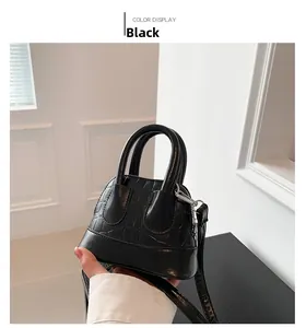Detail of black croc-embossed mini shell bag with metal hardware and top handle