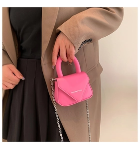 Detail der leuchtend rosa Mini-Umhängetasche mit Silberkette und Fashion-Aufdruck