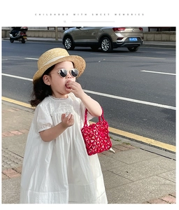 Detail of red beaded handmade kids handbag paired with a summer outfit and straw hat