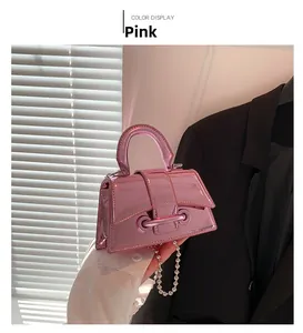 Detail of a shiny pink mini handbag with a metallic texture and beaded silver shoulder strap