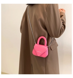 Detail einer pinkfarbenen Mini-Handtasche mit Kettenriemen und Griff, getragen am Model