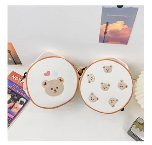 Gros plan de la broderie ours sur les sacs à bandoulière en toile beige pour enfants