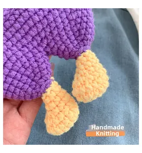 Detail of purple handmade crochet knit bag with yellow foot accents on denim background